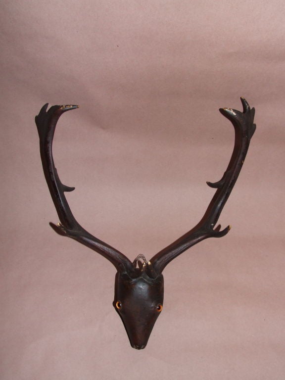 Circa 1850 English or Scottish folk-art trophy with carved and painted wood stylized stag's head with glass eyes, and incorporating real antlers.