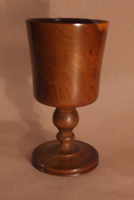 Nicely figured and beautifully turned yew wood goblet, the thinly walled vessel over balustrade turned step on shaped and turned foot, the whole turned from a single block of yew wood.

Treen