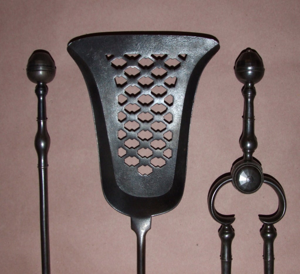 Fine set of three George III patinated steel fire tools, the facetted acorn finial over ring turned grip, the shafts with balustrade turning, the bell shaped shovel having diaper piercing, all with excellent rich patina