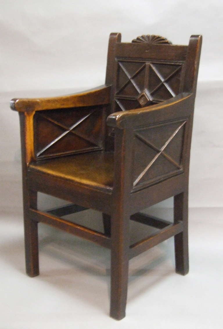 Most unusual English or Welsh Georgian wainscot armchair following the 16th and 17th century tradition of paneled backs and sides, but with early Regency motifs. This richly patinated oak chair has lattice work decoration, a carved fanlight crest