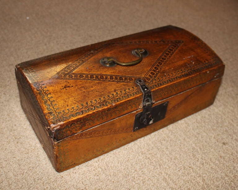 English 18th Century tooled leather document box with original brass handle and iron lock, the slightly domed top with diamond tooled design and arched boarder, still retaining some gilt decoration, the interior lined with original printed paper,