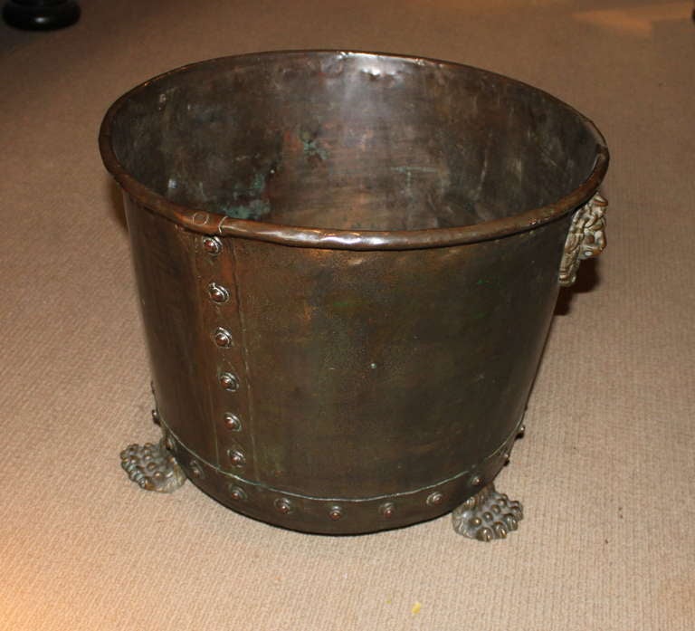 Good English 19th Century copper and brass log holder or planter having a rolled lip and hand hammered and riveted body, the lion masks and paw feet in brass, the whole with mellow patina and slight verdigris surface.

vessel, log bin, bucket,