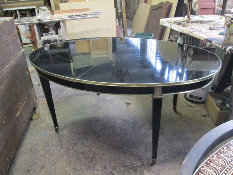 10 ft long Brass-Branded Lacquered Dining Table on Brass Sabots,
Table has three extensions, each measuring 18 inches in width,
without the extensions, the table measures 66 inches in diameter