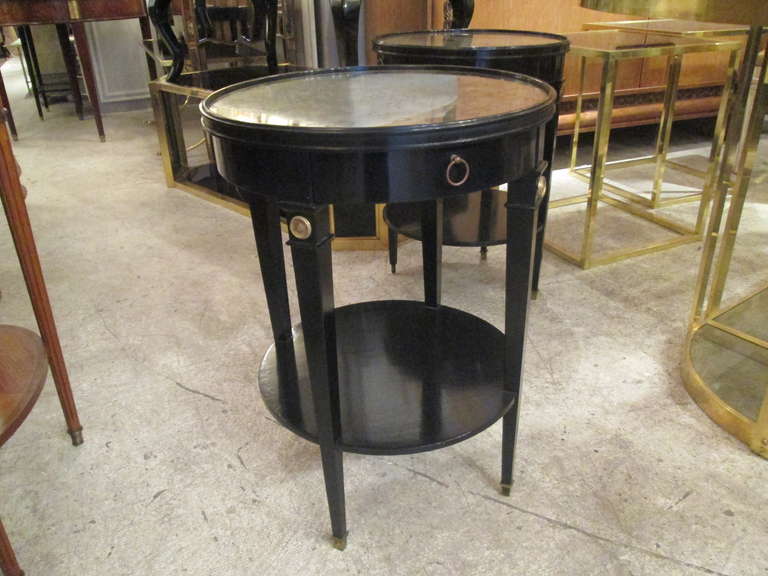Ebonized and bronze-mounted end tables with smoked glass top, on tapered legs ending in brass sabots.