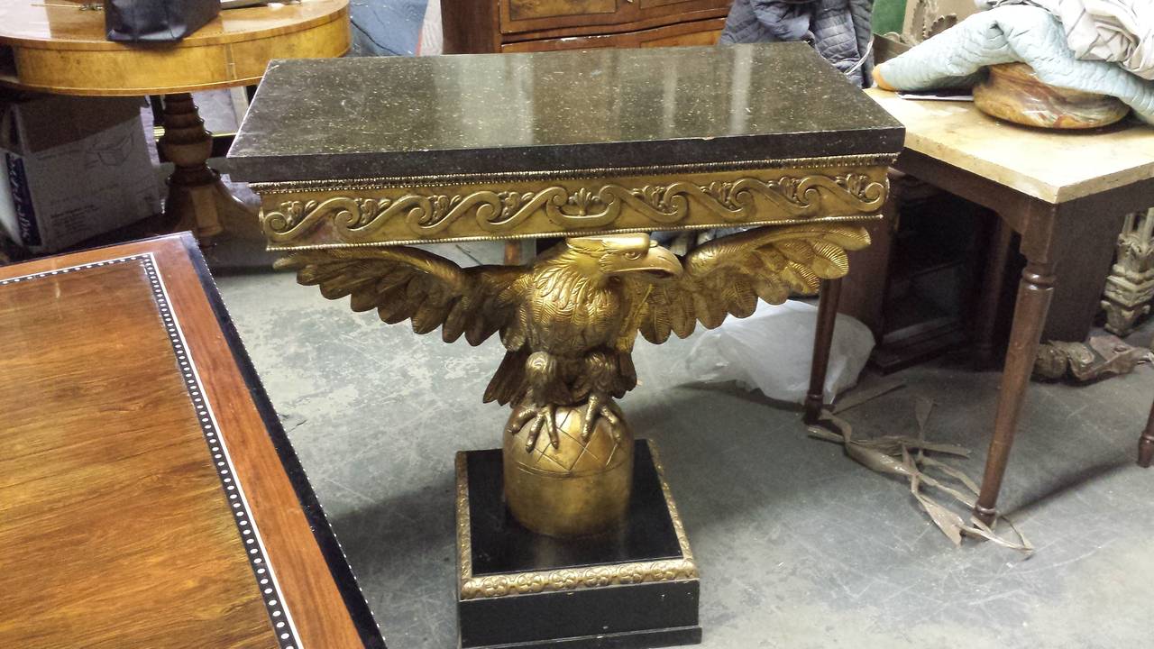 A pair of Georgian style giltwood eagle consoles with faux-marble tops.
