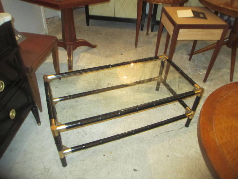 A Billy Haines ebonized faux-bamboo two-tiered coffee table with brass corners.
