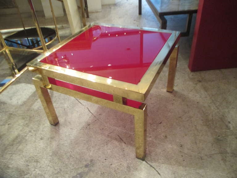 A pair of Mid-Century Modern brass tables with luminous red glass tops.