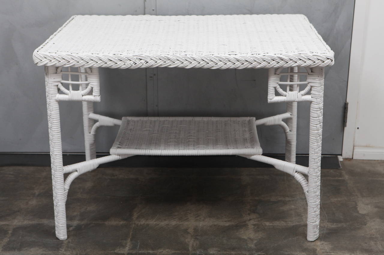 This nice white wicker table has reed woven to a bent wood frame with woven lower shelf and interesting corner details. The shelf is 12" from the ground.