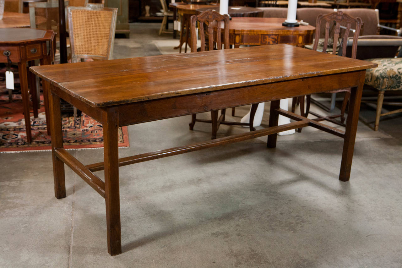 A handsome french farm table of a good size, stands on tapered square legs with carved stretcher bars. It has developed a nice mellow color over the past century and is sure to be a substantial and useful asset in any setting.