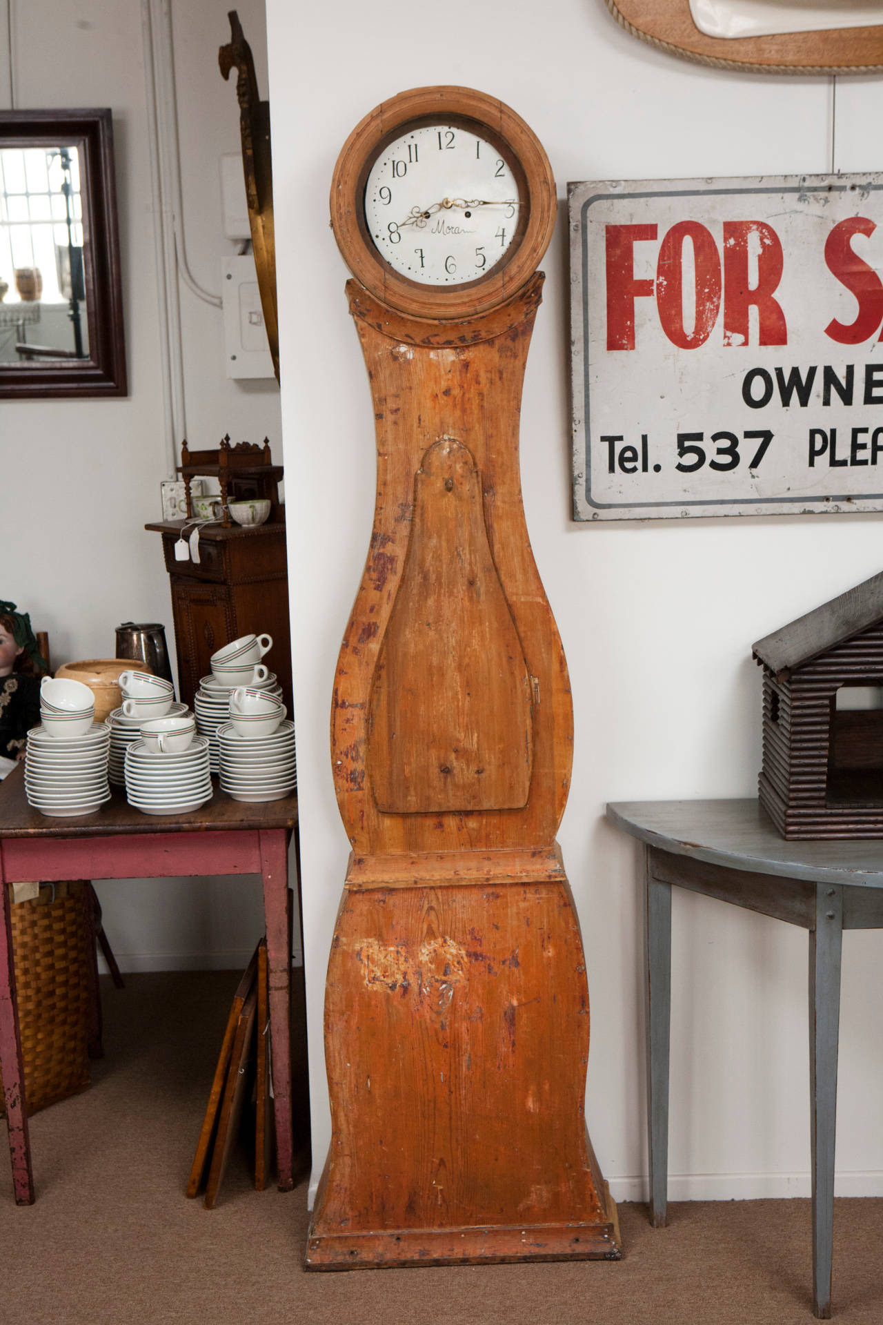 This slender Mora pine long case clock has been stripped down to its original burnt orange color with remnants of old paint. Gustavian Mora clocks are a type of long case clock which were made in, and derived their name from, the town of Mora in