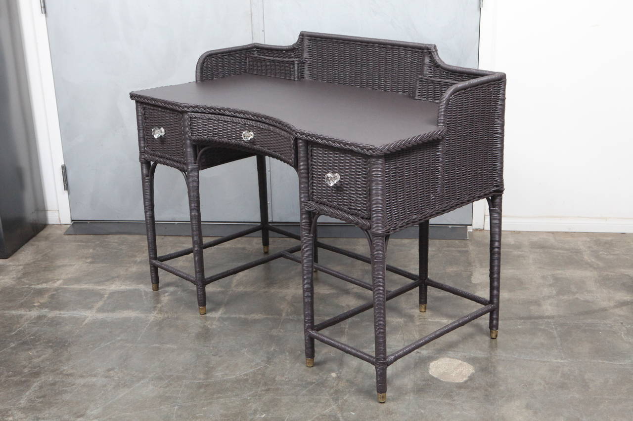 This wonderful example of wicker furniture from the 1920's is made of woven reed with a wood frame and wood desk surface. It has it's original glass drawer handles and has been hand-painted using Farrow & Ball brand paint.