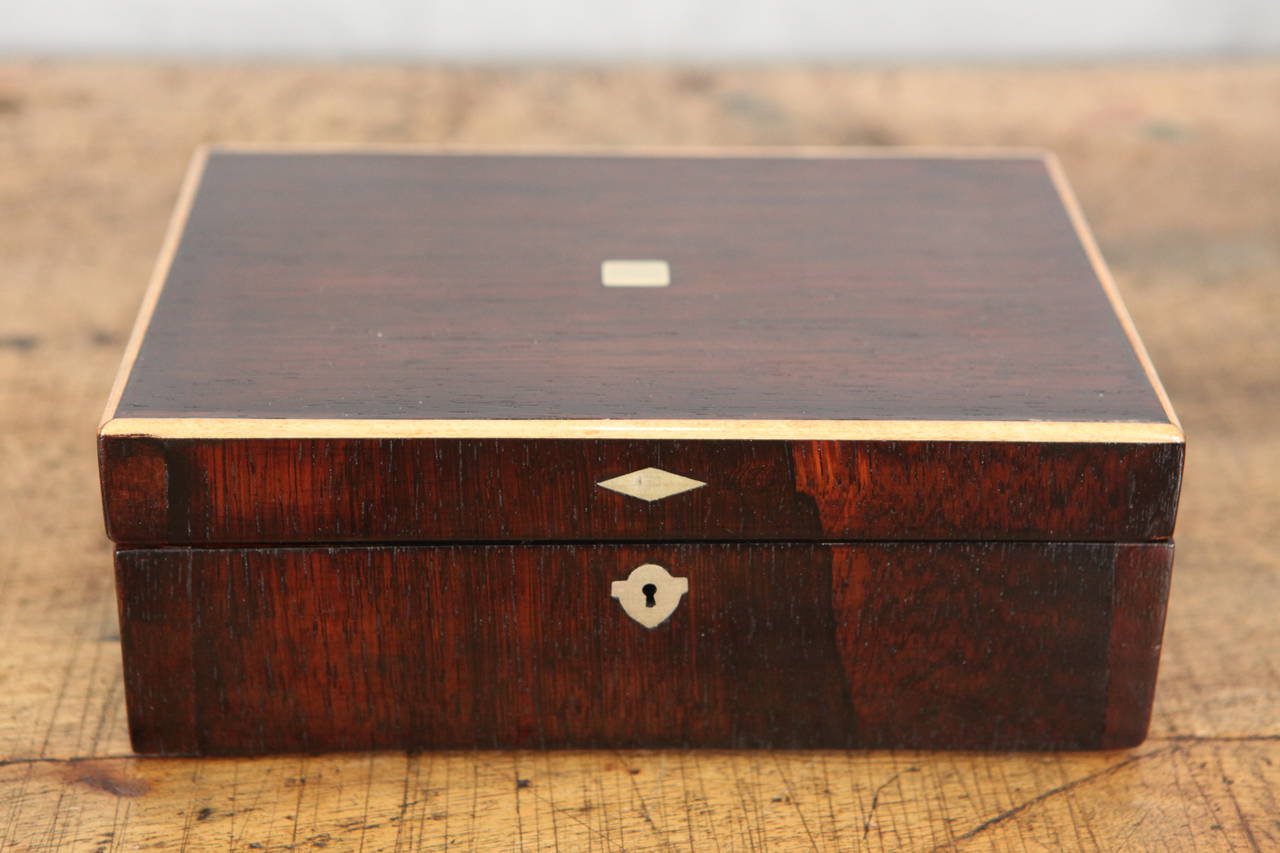 This beautiful English Mahogany Box with inlaid metal square decorative details and escutcheon has a light wood banding and Japanese block print paper lining.