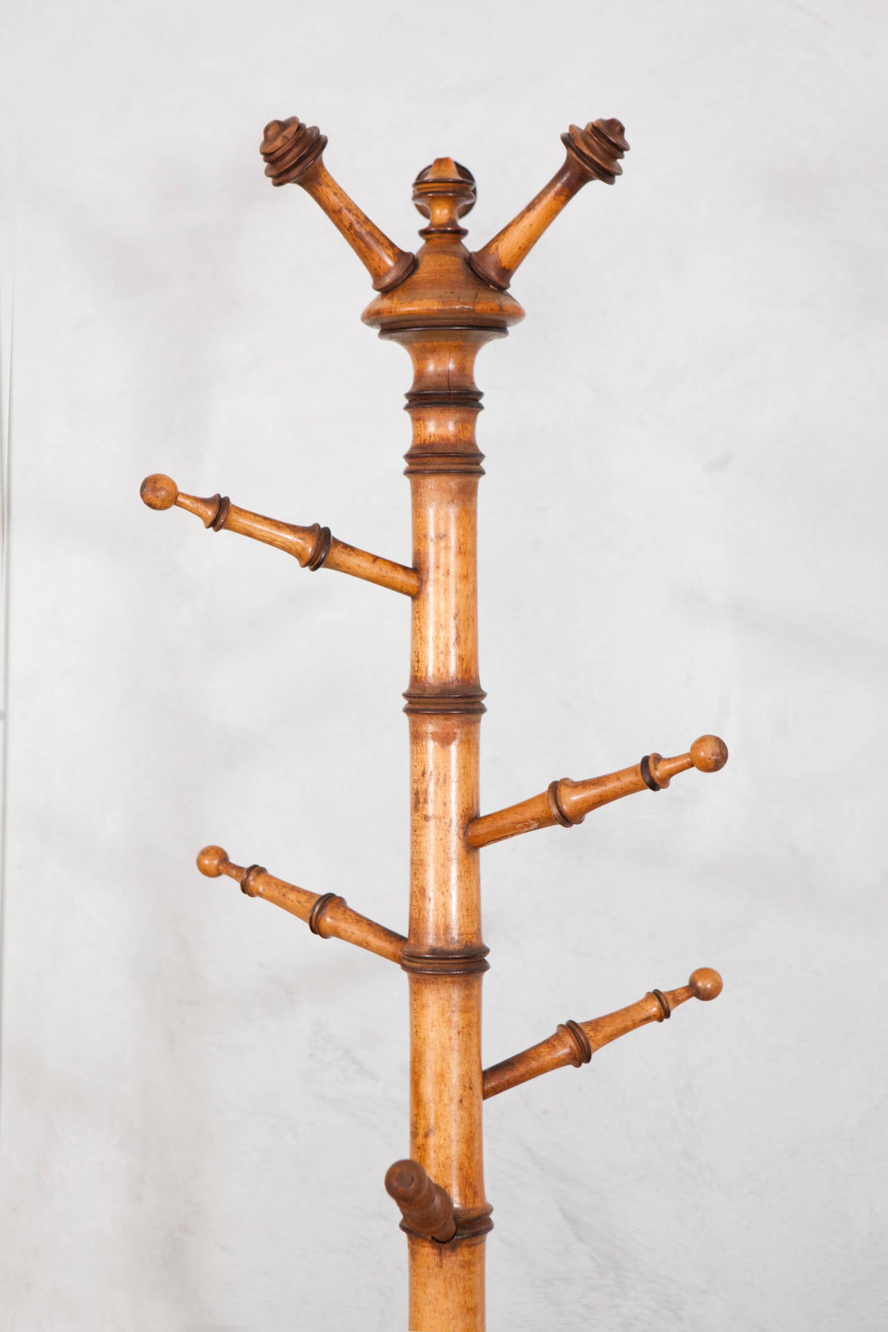 This dynamic branch like designed coat rack is made with turned wood in the faux bamboo manner. Note the delicately turned finials and decorative details in the bottom feet design.