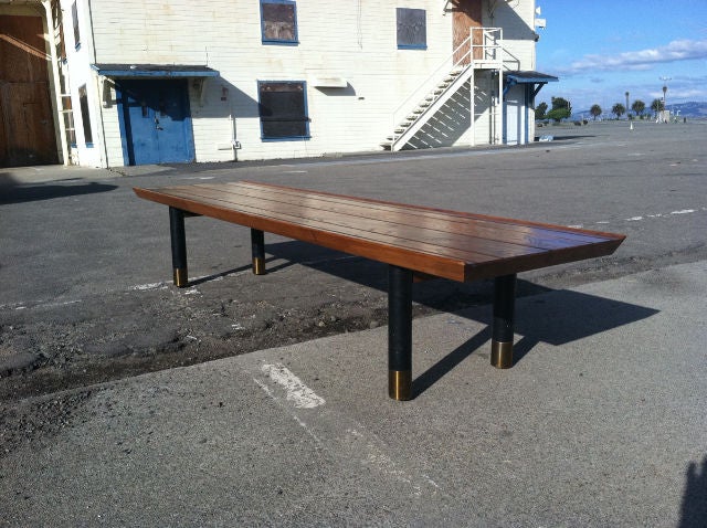 Custom low wood table or bench designed by Ed Wormley for Dunbar. Walnut top with visible dowels, ebonized wood legs with brass caps.