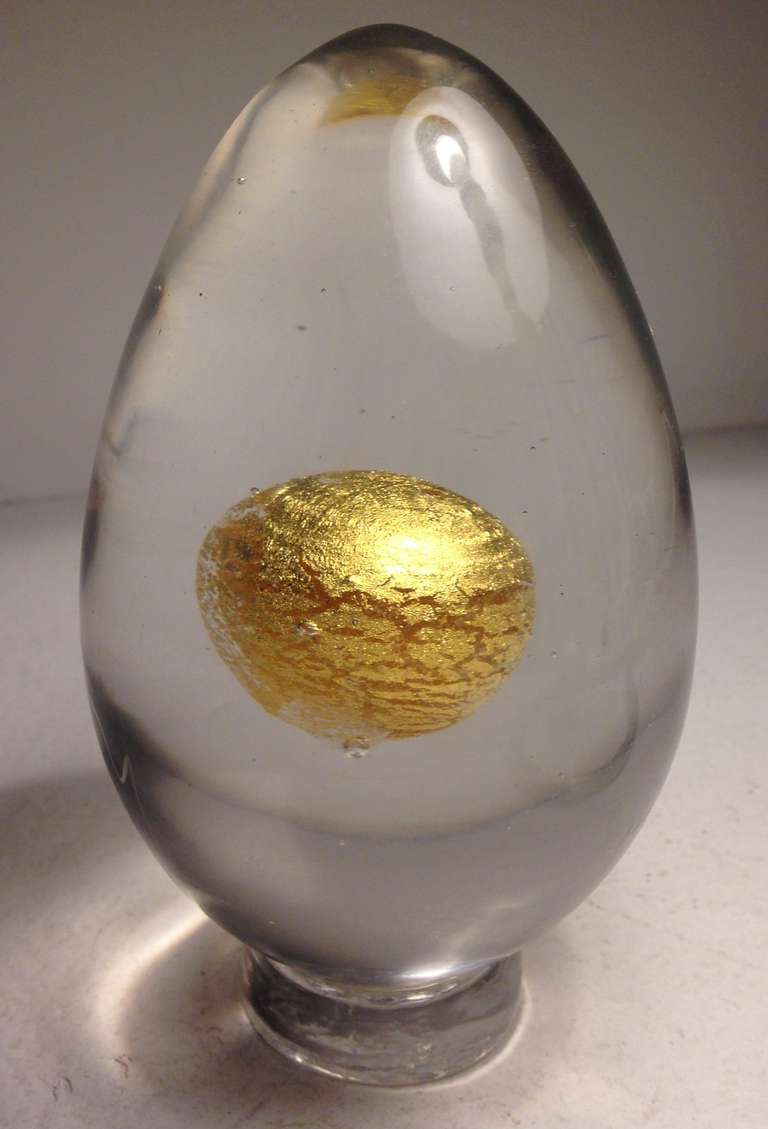 Tapio Wirkkala's design for a  series of egg sculptures venini produced in the mid-1960s.  Gold-leaf yolk in a clear glass egg rests on a glass pedestal.  Signed Venini Italia.