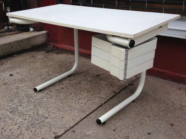White laminate top on white tube metal base with white plastic hinged drawers.  The writing surface inclines for use as a drafting table. For Bieffeplast.