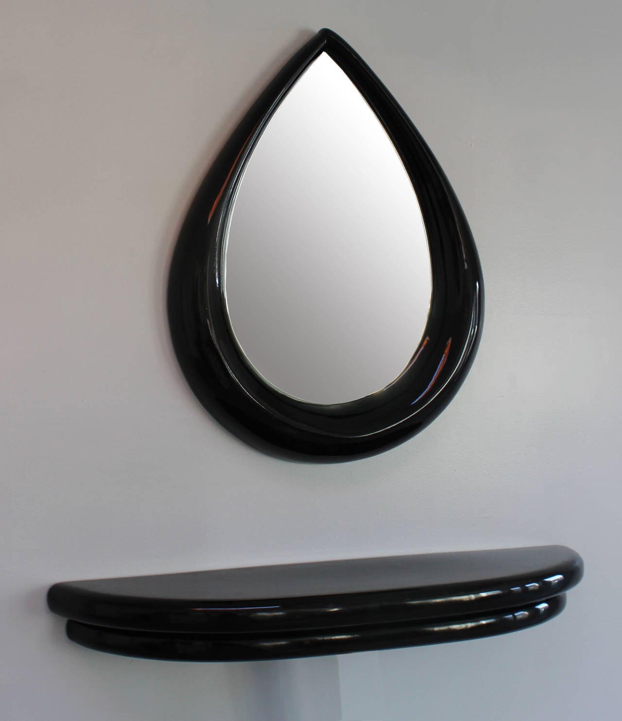 A modern, black lacquered wood frame teardrop mirror and wall mounted console.

mirror: 36