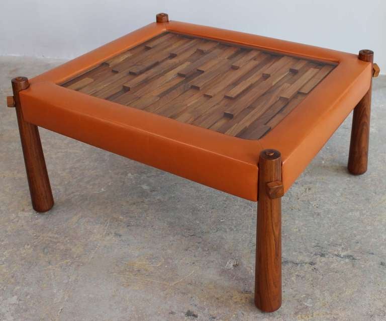 A Brazilian rosewood cocktail or side table with reverse tapered legs and mosaic puzzlework wood detail, framed by upholstered leatherette, designed by Percival Lafer.