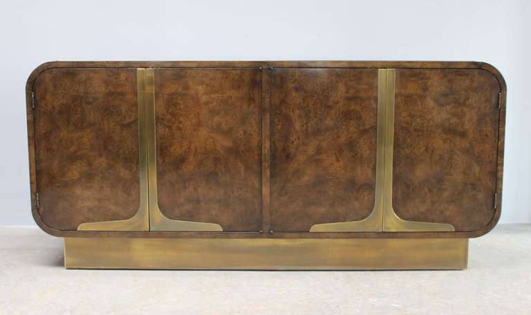 Handsome burlwood credenza with rounded corners and antiqued brass base and details.