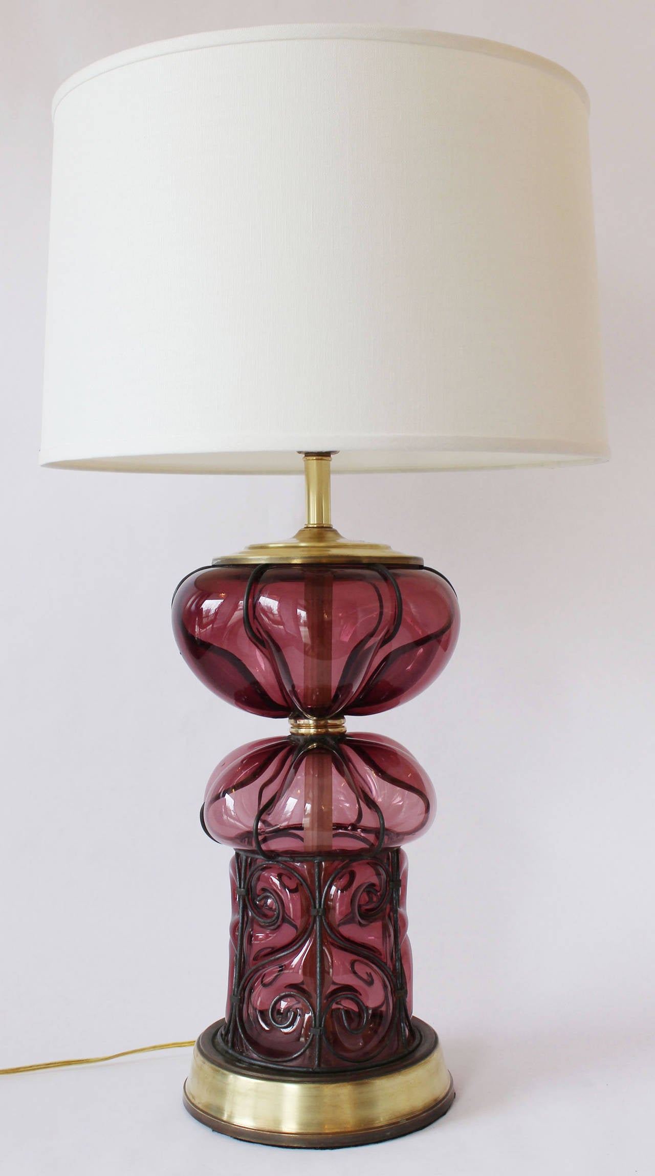 A stunning pair of modern regency style violet blown glass lamps with enameled, decorative metal and brass details.

Shades for photo only.
18.5