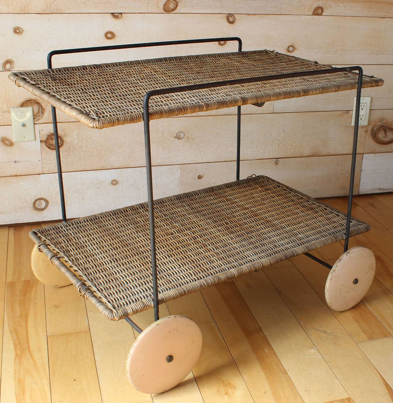 An iron frame and woven rattan server or trolley with wood wheels. A rare and early example of designer Carl Auböck.