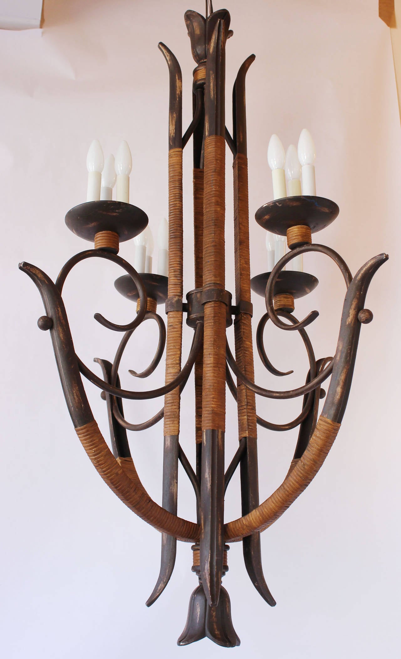 A distressed metal and rattan chandelier with twelve candle sockets.