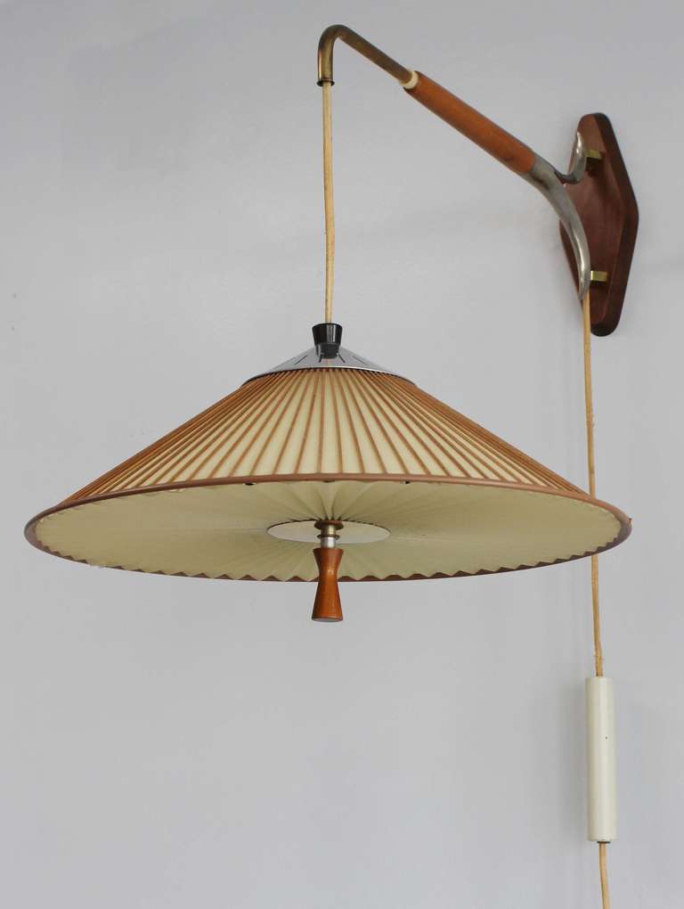 A wonderful mid-century cantilevered wall lamp with walnut and metal details, and vellum and wood shade, with accordian vellum diffuser. Also pivots to each side. Designed by Gerald Thurston for Lightolier.
Shade is 11