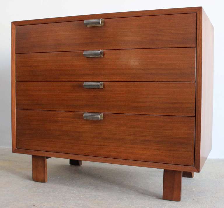 Classic walnut four-drawer dresser with metal pulls, designed by George Nelson for Herman Miller. Larger matching dresser with cabinet and cantilever, mirrored vanity piece with bench also available.