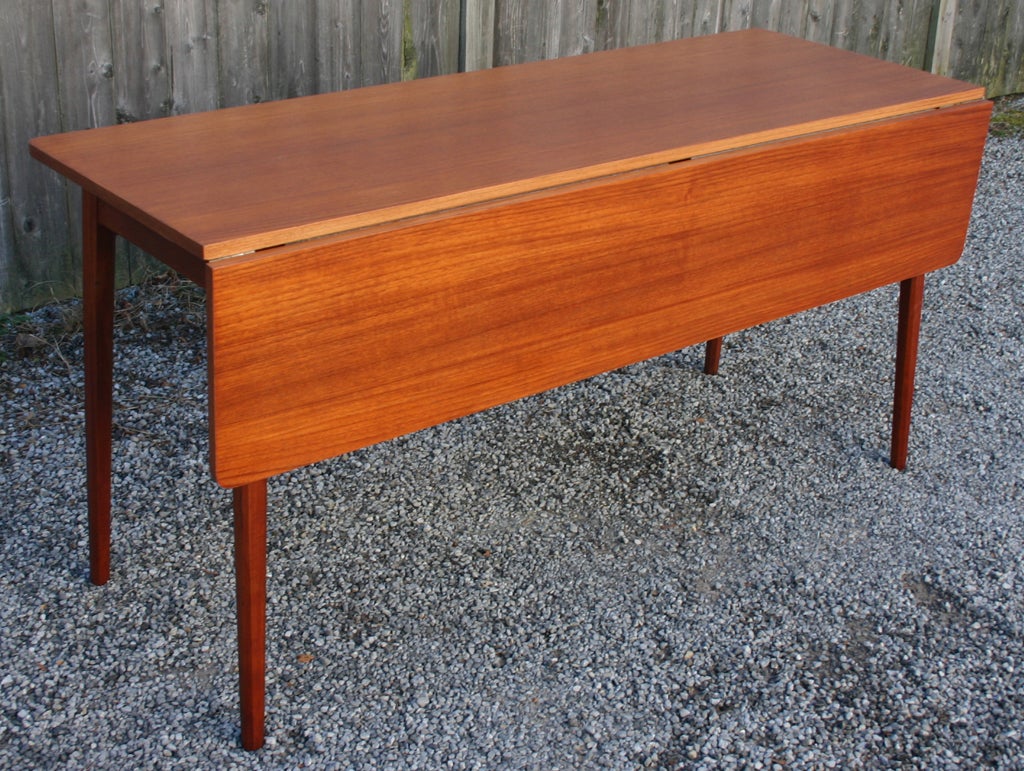 Compact teak drop leaf dining table or console. seats eight when open.