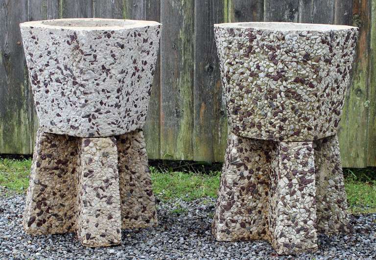 A pair of eight-sided concrete, stone mosaic planters with pyramidal bases.