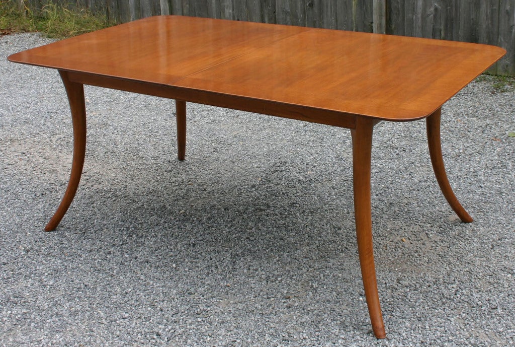 Classic sabre leg walnut dining table with two 17 inch leaves, designed by T.H. Robsjohn-Gibbings. Chairs and Sideboard also available. 104 inches fully extended