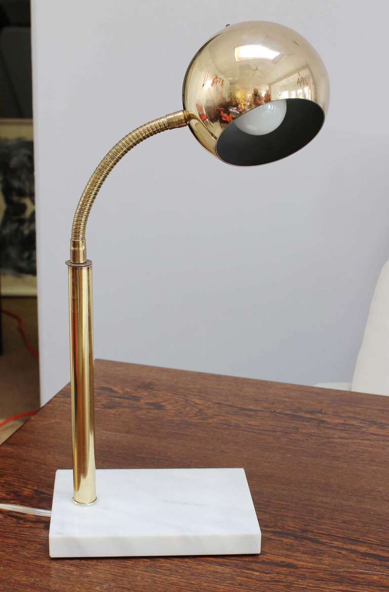 A patinaed brass gooseneck reading lamp with Carrera marble base; adjustable neck.