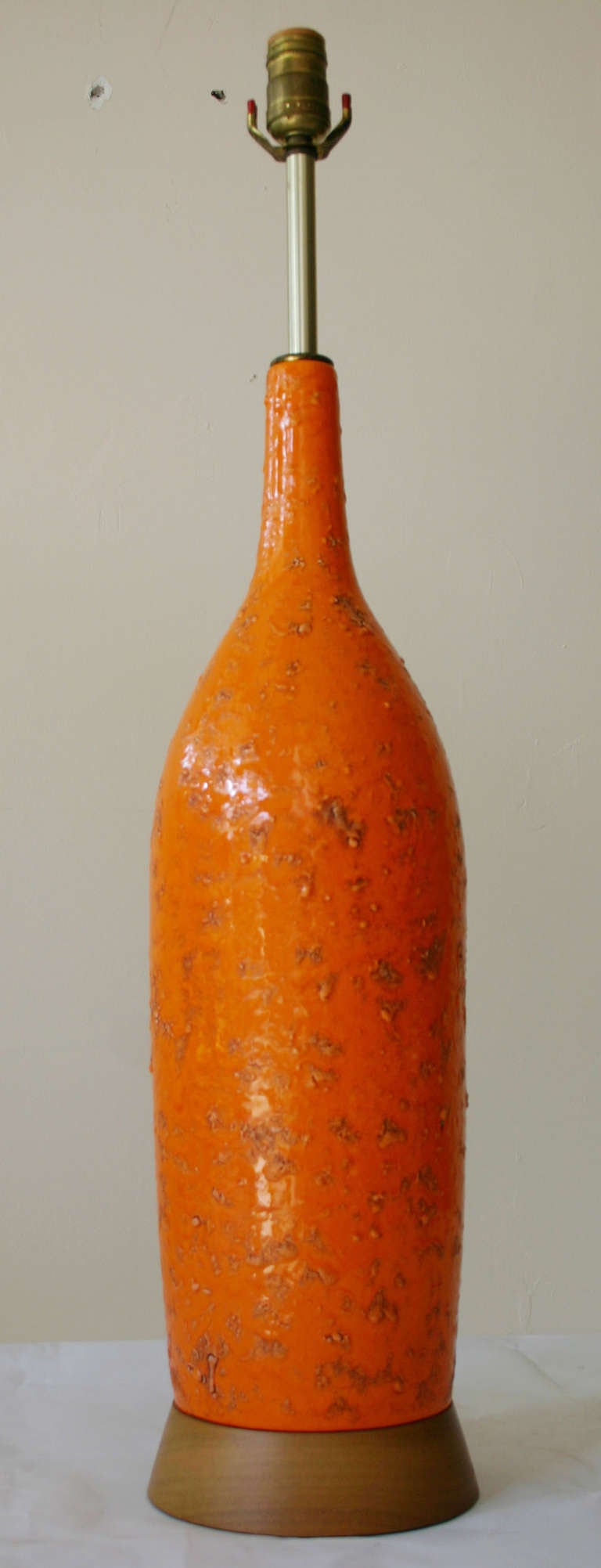 Tall, orange volcanic glazed ceramic lamp with walnut base, attibuted to Fantoni.