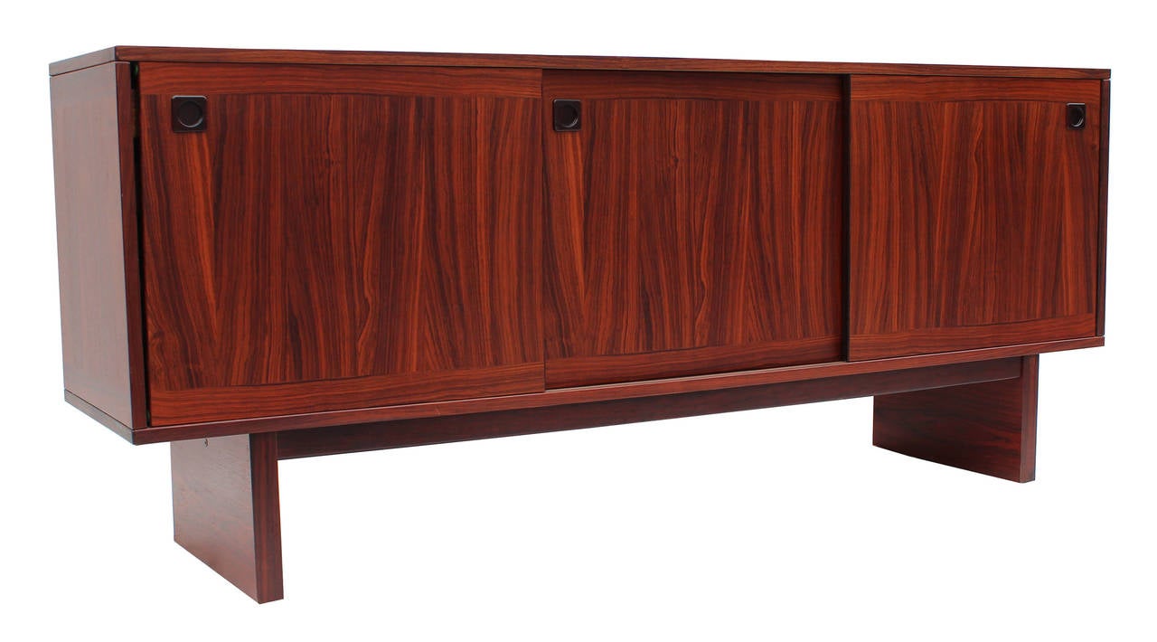 Handsome rosewood sideboard or storage cabinet with sliding doors and recessed pulls. 

Additional top piece with glass shelves and doors also available. 
Measures: 70.75w x 26.63h x 11.75 
See pictures.