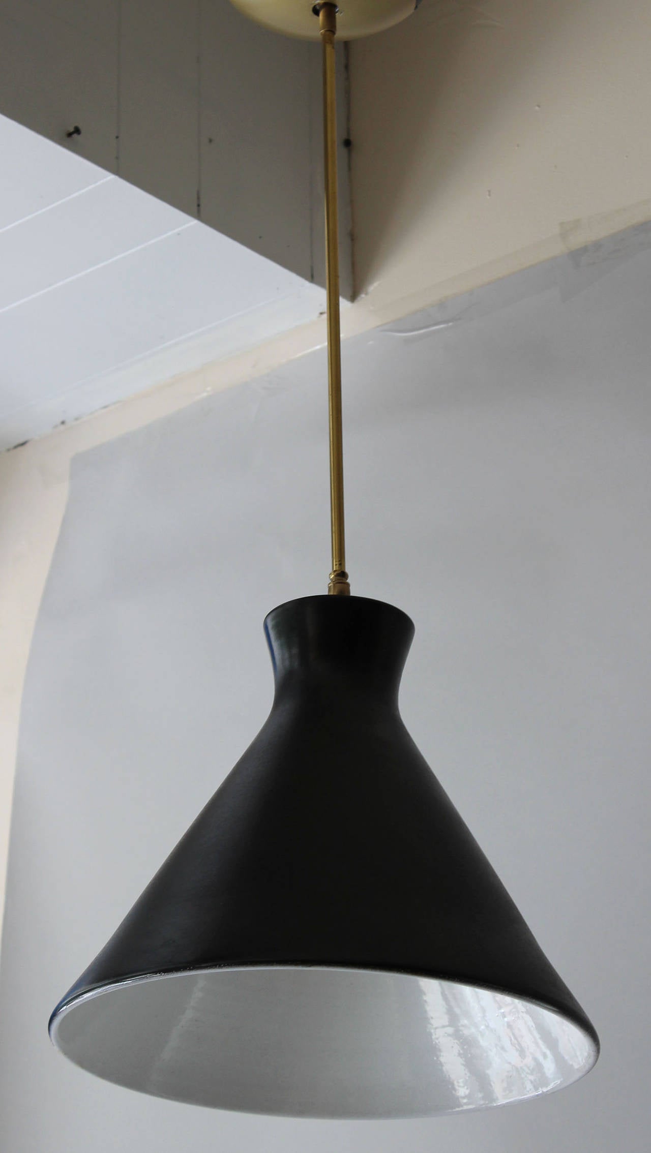 A stunning matte charcoal black glazed pendant with gloss white interior, and brass hardware, by Upsala Ekeby, Sweden. stamped on top.

20 inch stem