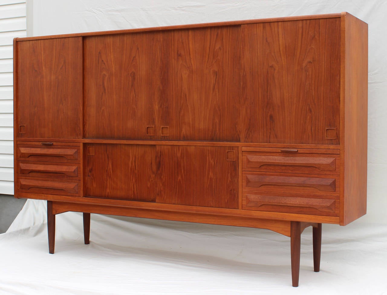 A handsome teak cabinet sideboard with various interior spaces for efficient storage and display.