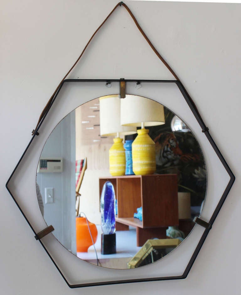 Handsome iron frame hexagonal mirrors with solid brass clips and vintage patina round mirror and leather strap hanger, in the manner of Adnet.