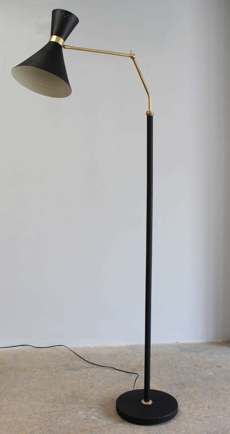 Adjustable and rotating black metal floor lamp with brass details.