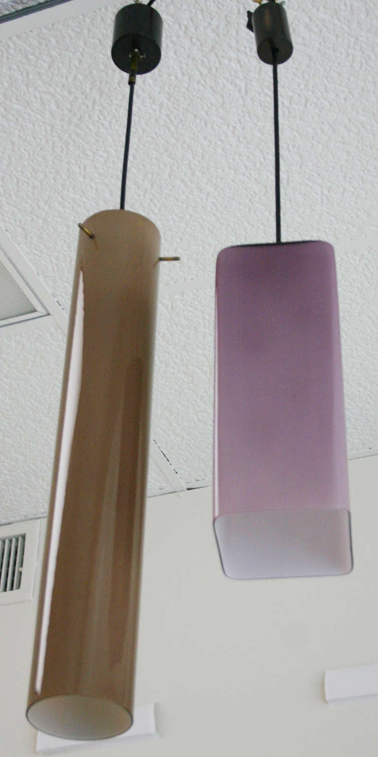 Two pendants -- one brown and one violet -- with brass and black enamel hardware, and white glass interiors. Priced separately. Brown $1800 / sale $1200; violet $1500 / sale $1000.