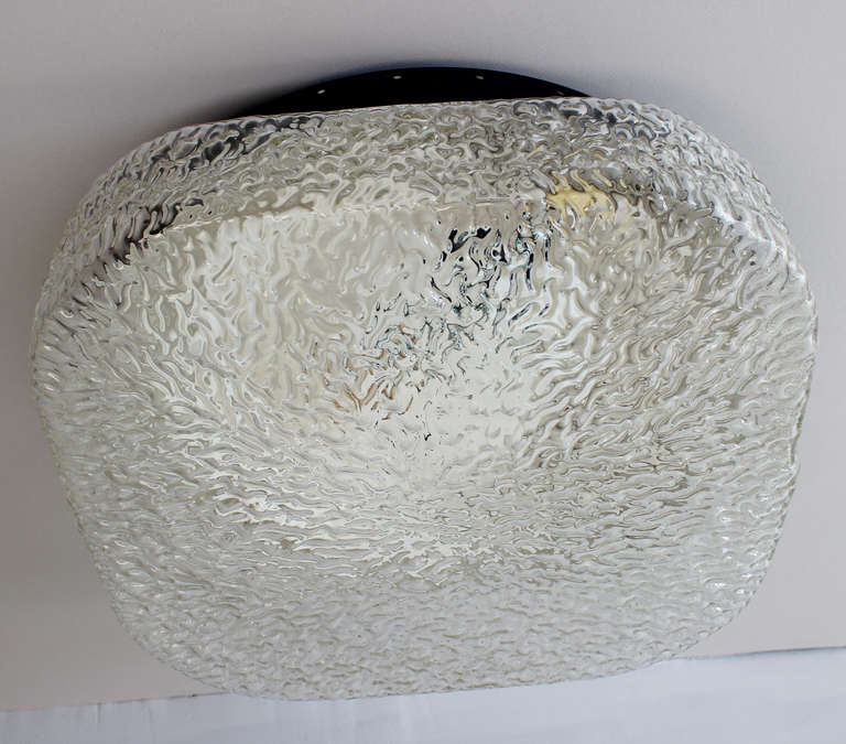 A large, textured glass ceiling light with black enameled metal hardware by Limburg, Austria.