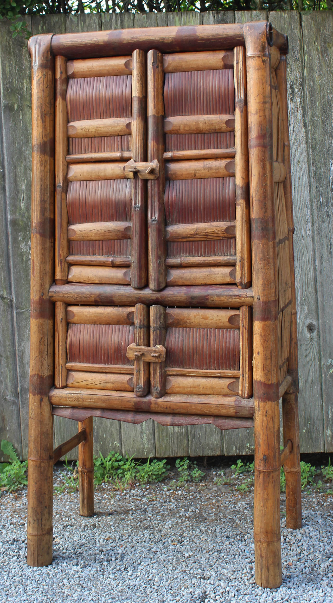 An early 20th century Asian bamboo cabinet with shelves and wood latch details.