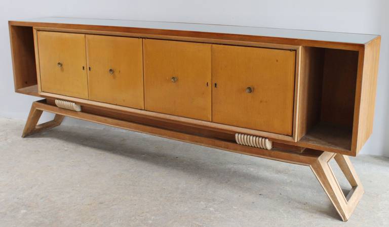 A modern Italian beechwood buffet console with carved details and brass hardware and light blue-grey glass plateau, in the manner of Paolo Buffa.