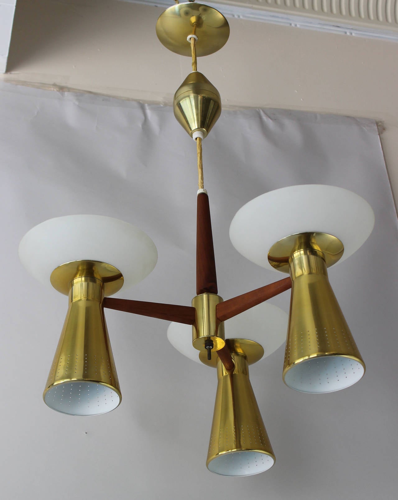 A brass and teak pendant chandelier with milk glass diffusers in the style of Paavo Tynell. Six sockets.

18 inch expandable-retractable rope.

complementary delivery within 30 miles.