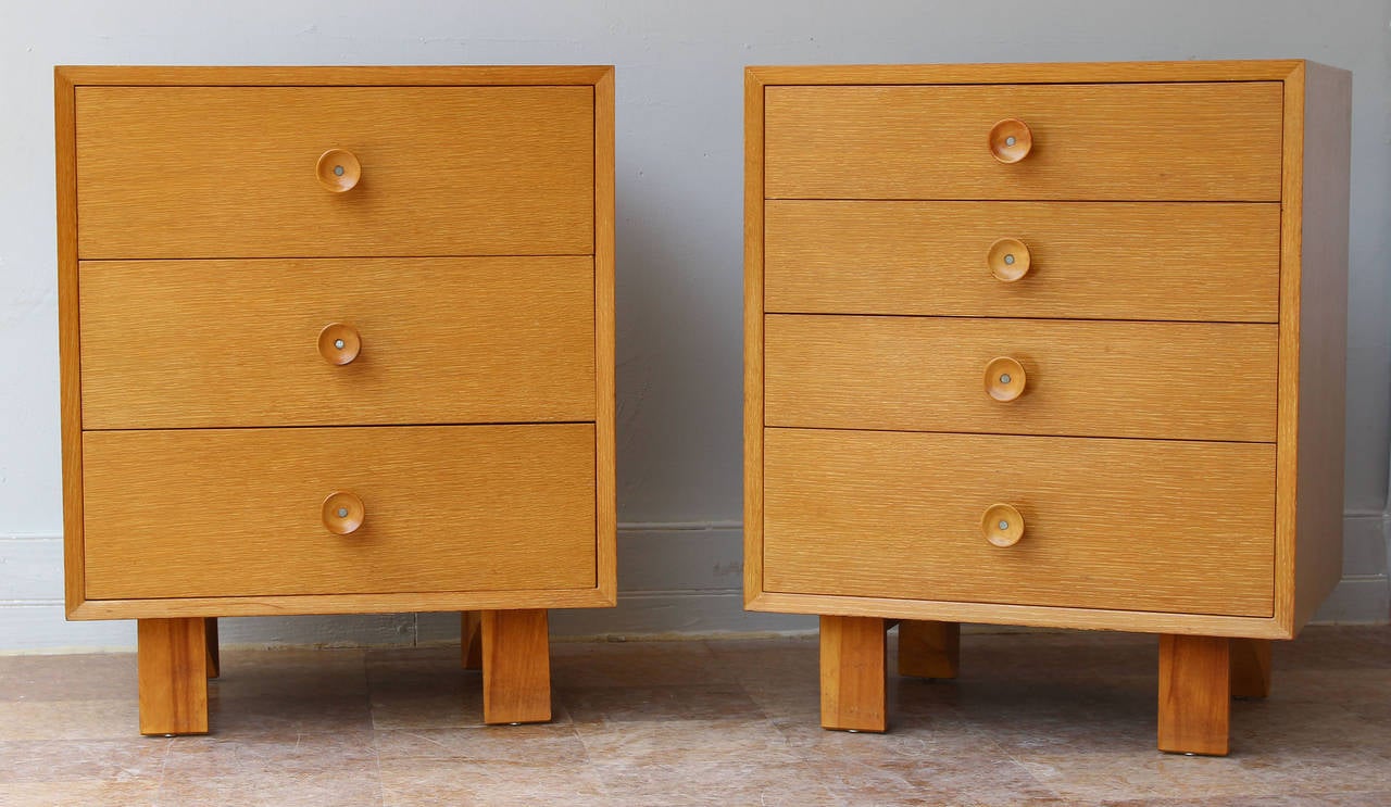 A pair of oak nightstands or small dressers with wood pulls and legs, by George Nelson for Herman Miller. Note dressers have three and four drawers. Vanity pieces also available -- see pictures.
Matching pair mirror-matched dressers also available