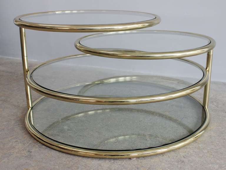 Tubular brass and glass 4-tier coffee table with swiveling top layers.

Opens to 82 inches wide
