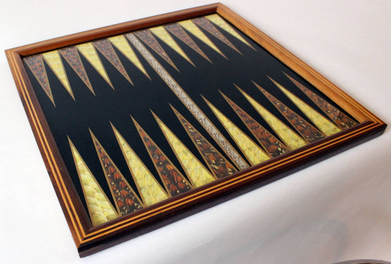 An exceptional backgammon game board of layered butterfly wings under glass and an inlaid exotic wood frame.