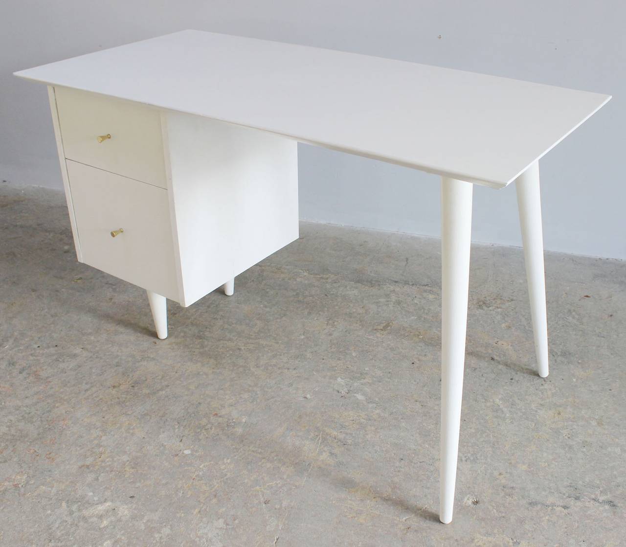 The classic one-side drawer Planner Group desk with brass drawer pulls and formica top, by Paul McCobb.