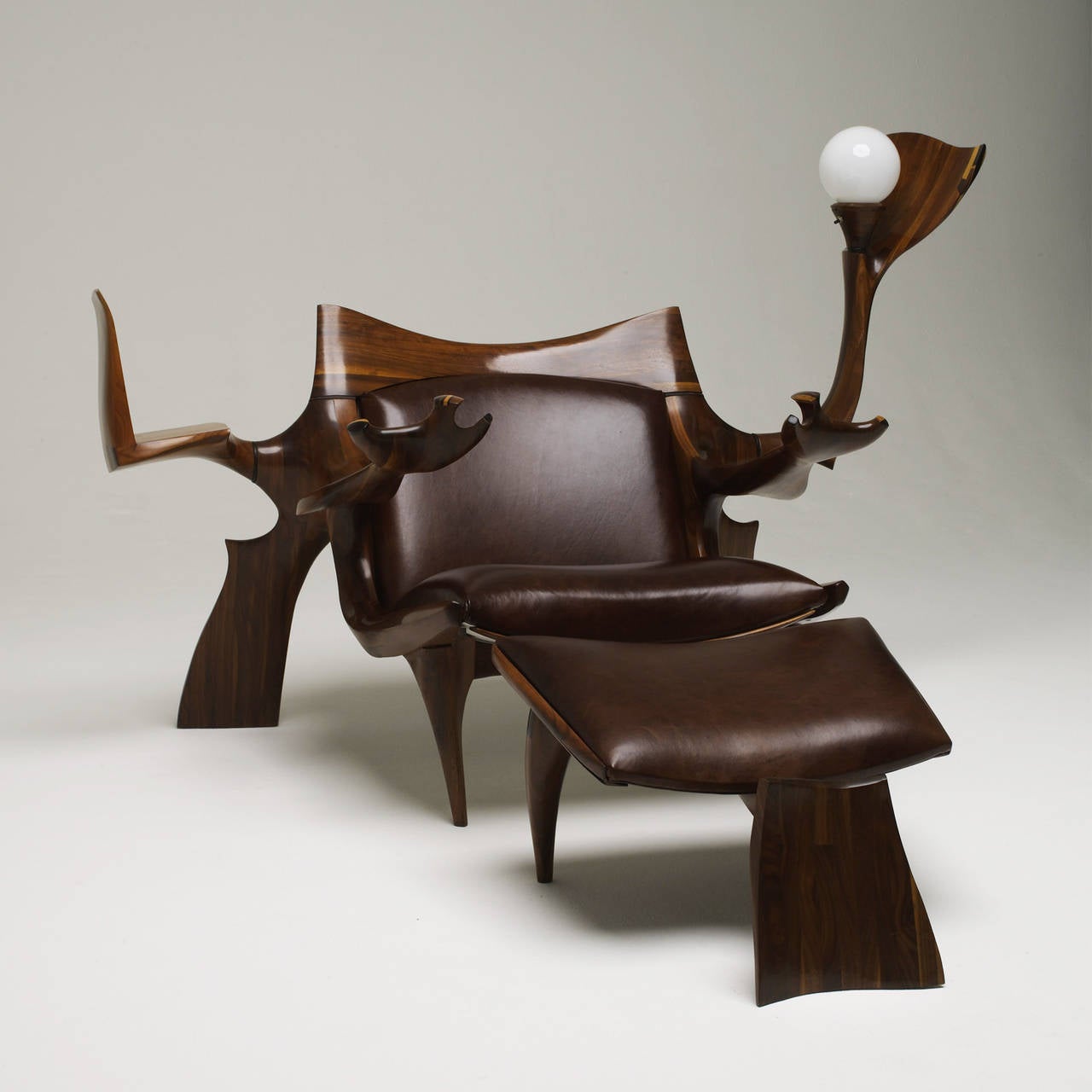 Exceptional, unique lounge chair and ottoman is a fantastic example of Hopkins' unrestrained artistic expression. Laminated construction allowed Hopkins to create elegant large-scale pieces. Known for combining the utility of several items into one