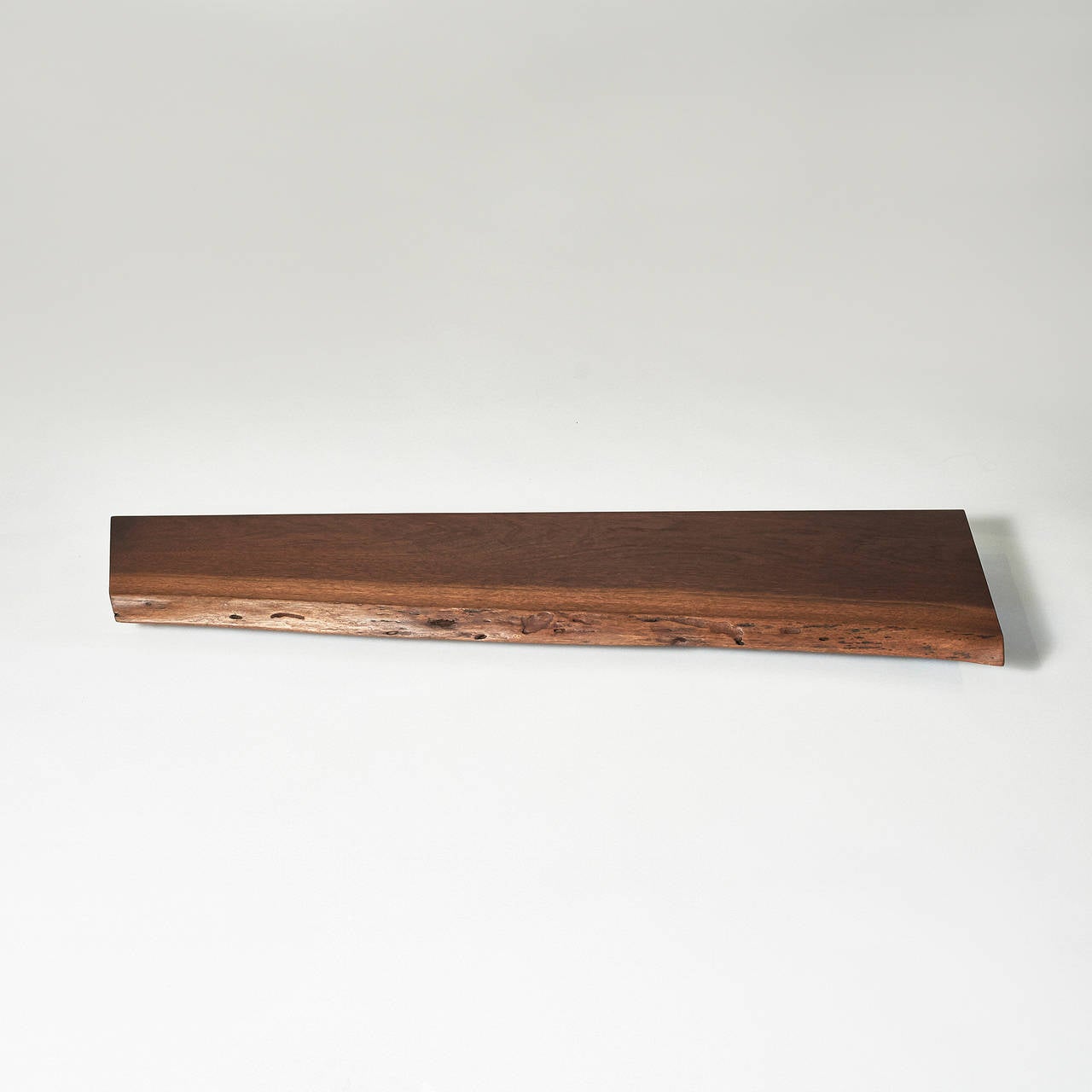 A beautiful free edge walnut wall-mounted shelf measuring 46 inches in width. Excellent original condition. The shelf is accompanied by the original client's receipt from 1957 and a letter of authenticity, both from the Nakashima Studio. 

