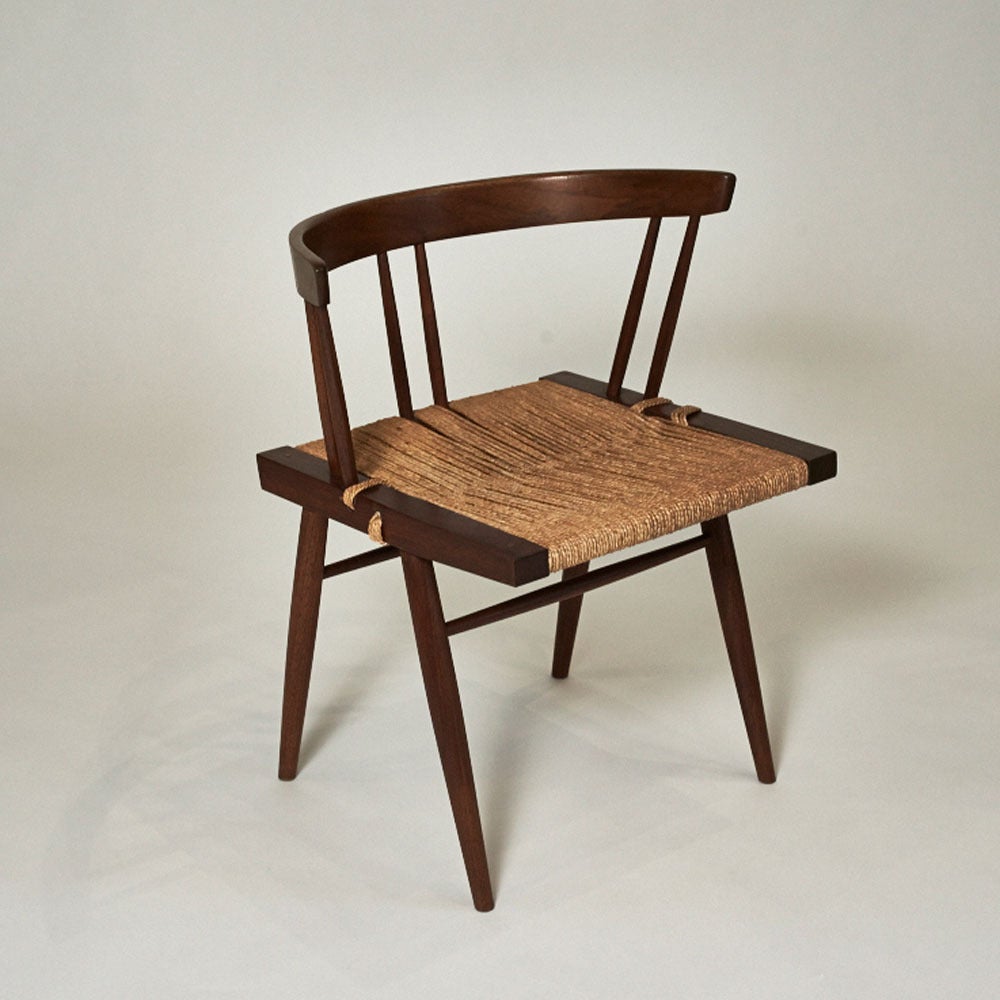 This elegant black walnut chair features grass caning woven on the seat's frame, rendering it extremely comfortable and light. The black walnut seat frame and back rail are supported by four tapered legs of the same wood. The top rail is supported